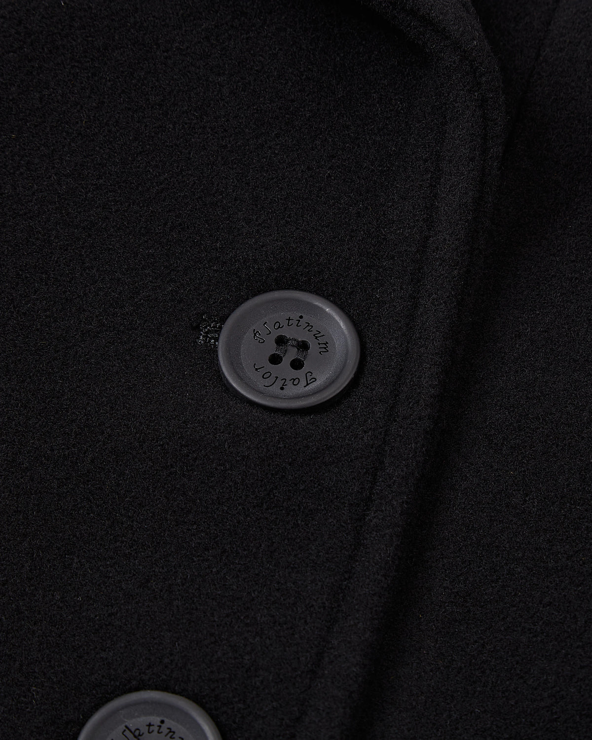 Close up of the wide lapel and collar on the black wool overcoat