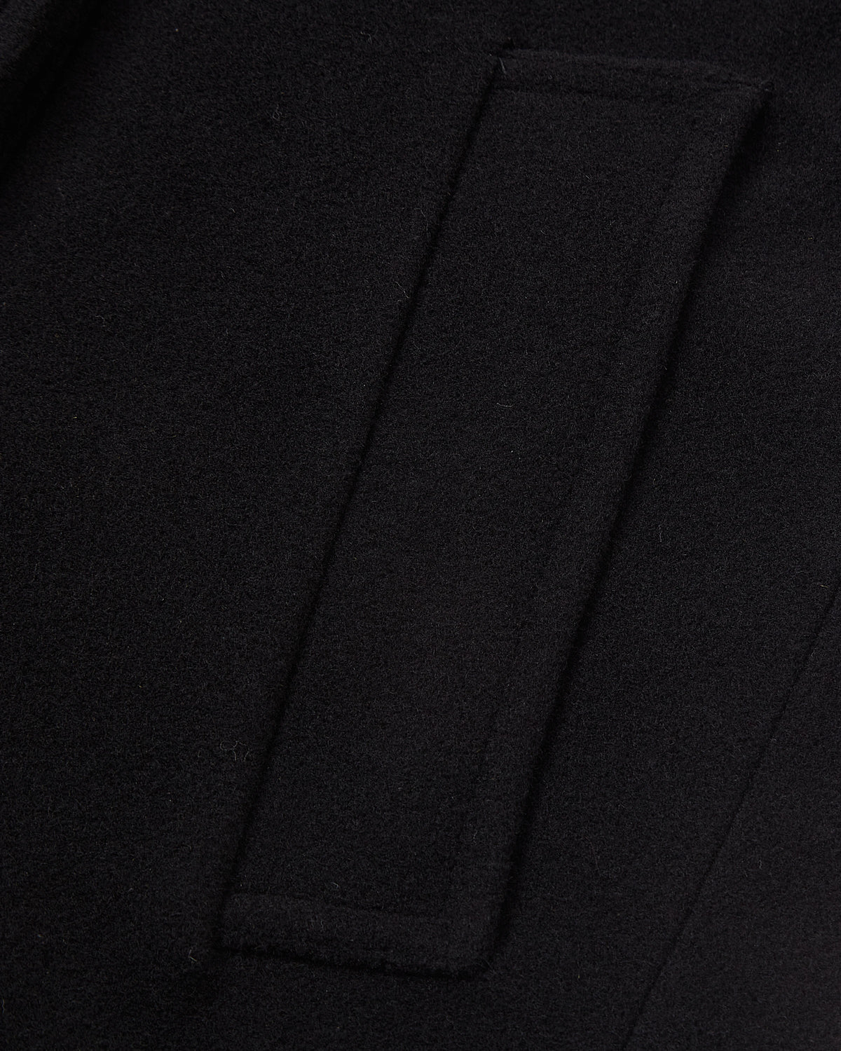 Detail of the double breasted buttons on the black wool overcoat