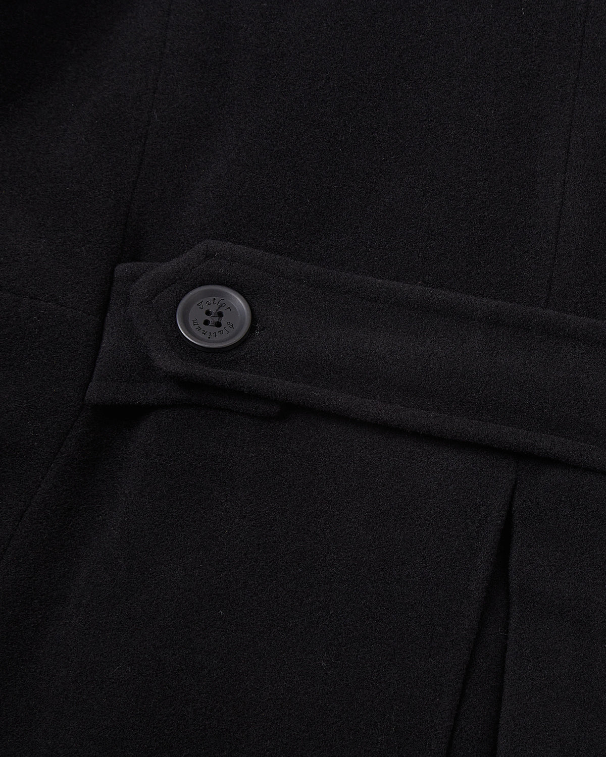 Close up of the cuff and sleeve hem on the black wool overcoat